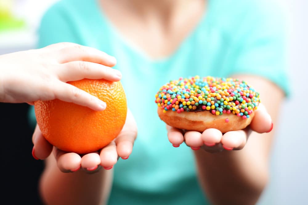 Orange oder Donut? Eine Kinderhand greift zur Orange.