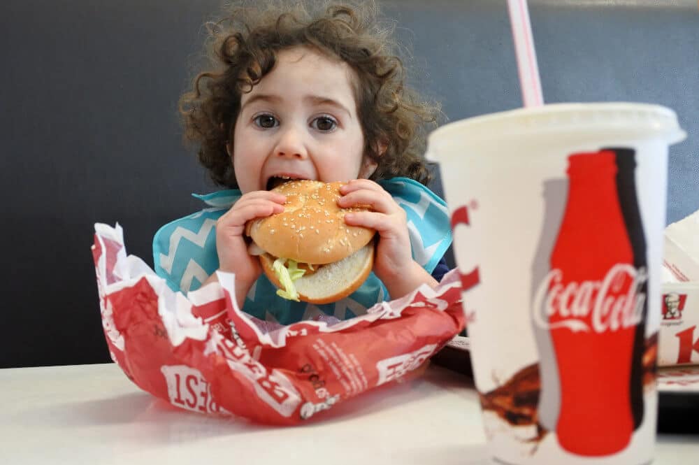 Kleines Mädchen mit Burger und Coca-Cola