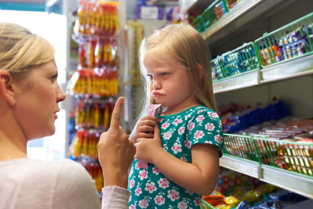 Mutter diskutiert mit Mädchen über Süßigkeiten im Supermarkt