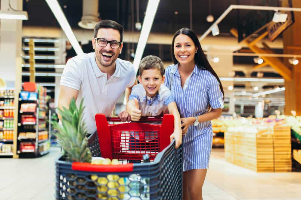 Kind beim Einkaufen im Supermarkt, zusammen mit Vater und Mutter