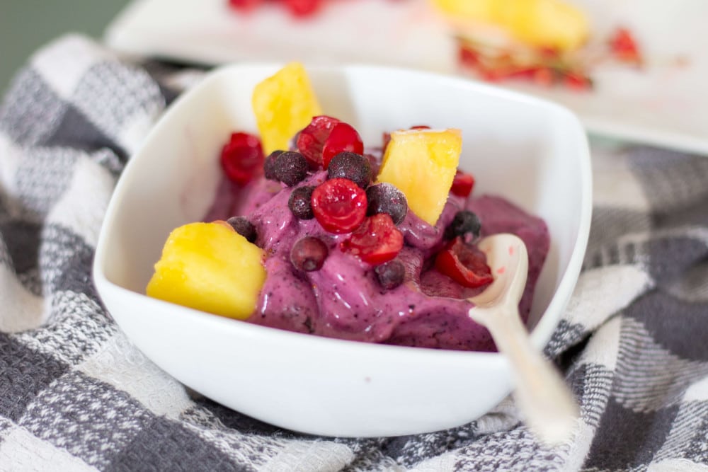 Lila Nicecream mit Beeren und anderen Früchten als Topping